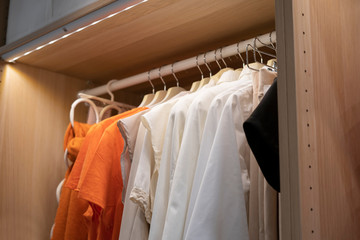 Fashion t-shirt hanging on metal rack in wardrobe closet with led light
