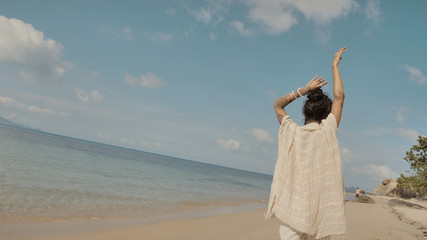 Fototapeta na wymiar Seductive oriental woman at hot day under sun by the sea coast, walking and sensually posing