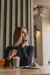 portrait of a beautiful young blonde woman with coffee. girl sitting in a cafe in the morning with coffee and croissant, Breakfast in the morning in a restaurant