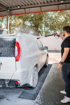 strong man washing car at self carwash outdoors