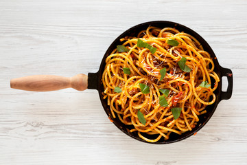 Homemade Bucatini all Amatriciana Pasta in a cast iron pan on a white wooden background, top view....