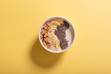 Healthy pineapple, mango smoothie bowl with coconut, bananas, blueberries and granola. Top view scene on a bright background.