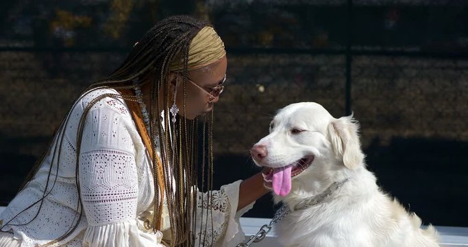 Black African American woman playing and talking to friendly dog in Los Angeles, California, 4K