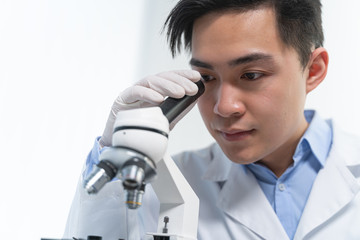 Kind young researcher looking through a microscope