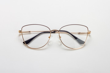 The golden female medical eyeglasses with folded temples on a white background