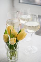 White wine. Dry wine. Glass of wine on the backgound table. Spring flowers. Yellow tulips.