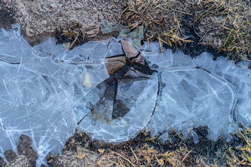 A crust of broken ice on a puddle. Copy of the space.