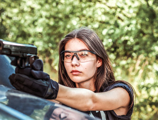 Girl in tactical clothes with a gun. Military woman. Black T-shirt and pants. Holster.SWAT