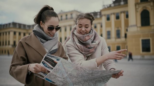Two young girls tourists look at the map, have fun, laugh and argue. Vienna, Austria (Europe).