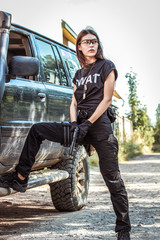 Girl in tactical clothes with a gun. Military woman. Black T-shirt and pants. Holster.SWAT