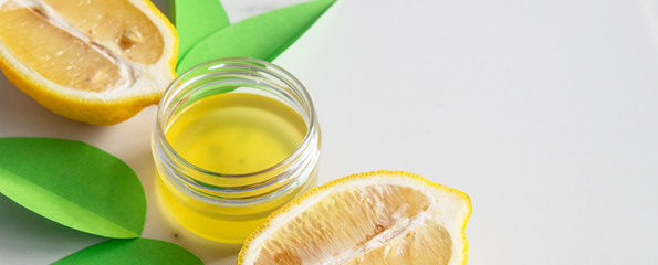 Cosmetic oil for body or face with lemon extract and citrus fruits on grey marble background with...