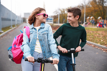 Fototapeta na wymiar Active teenagers riding kick scooters outdoors