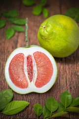 Red Pomelo fruit with leaves on the old wooden table.Whole pomelo with slice on wooden Background