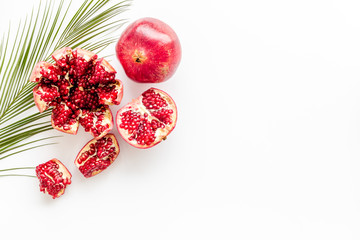 Ripe pomegranate fruit near leaf on white background top-down copy space