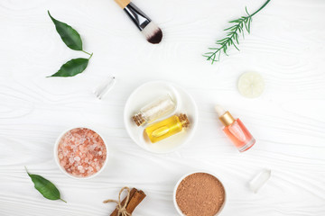 Homemade spa cosmetic set with salt, clay mask and oil on white wooden background. Copy space. Flat lay style.
