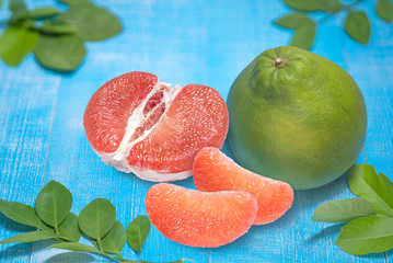 Red Pomelo fruit with leaves on the old wooden table.Whole pomelo with slice on wooden Background