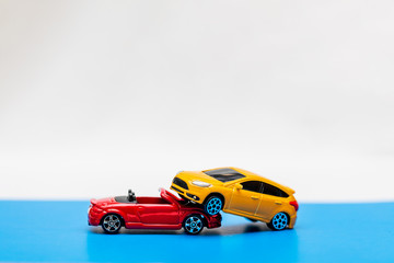 Close-up of a collision of two toy cars on a white background. Green and yellow cars collided. Accident concept. Auto insurance.