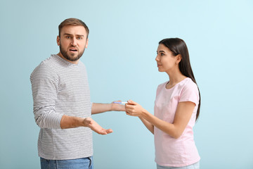 Emotional young couple with pregnancy test on color background