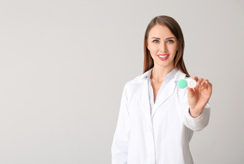 Ophthalmologist with contact lenses on light background