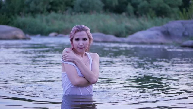 Sexy blonde girl in a white t-shirt comes from the water. Slow motion.
