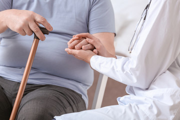 Female doctor with senior man suffering from Parkinson syndrome in clinic