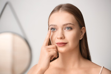 Young woman with contact lens at home