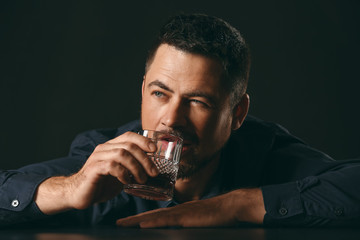 Mature man drinking alcohol on dark background