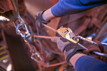 Male rope access technician inspector hand wearing a safety glove performing inspecting descender ensure rope is lock connecting correctly on rope prior to abseiling construction site, Australia   