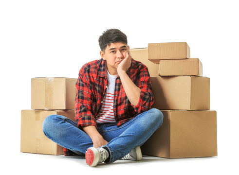 Asian man with moving boxes on white background