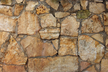 background of a solid stone wall of cement, limestone, sand and light multi-colored cobblestones with an uneven surface, of different sizes and shapes