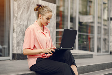 Girl with laptop. Student study in a city. Lady in a pink shirt.