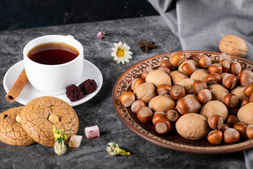 A cup of tea with cookies and nuts
