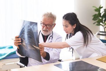 Senior male doctor is giving women doctor visiting radiologist for x-ray exam.