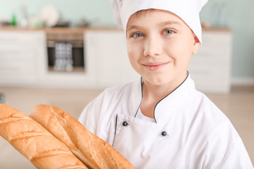 Cute little chef with bread in kitchen