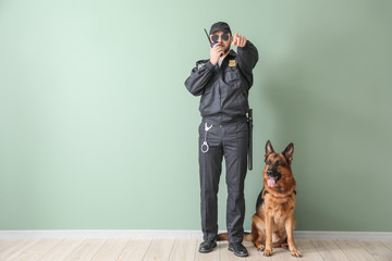 Male police officer with dog near color wall