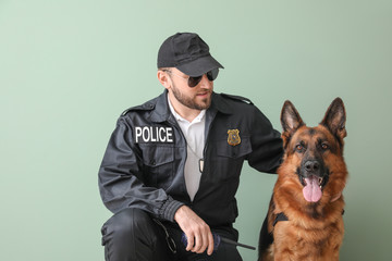 Male police officer with dog on color background