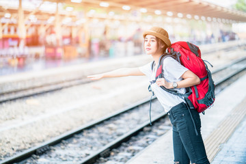 Portrait of young beautiful girl with backpack, standing looking map at the train station 