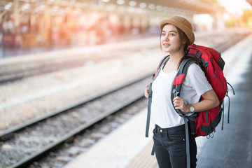 Portrait of young beautiful girl with backpack, standing looking map at the train station 