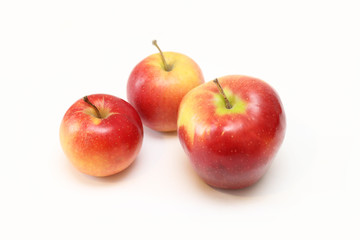 three red apples of different sizes on a white background