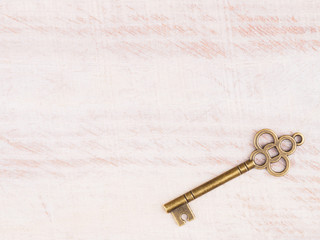 Old bronze key on light brown wooden background with copy space