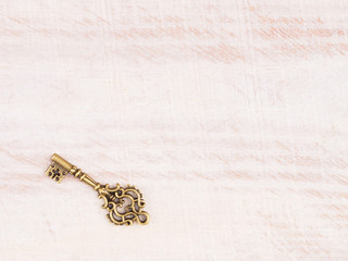 Old bronze key on light brown wooden background with copy space