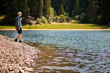 Tourist young man walking on the forest lake beach in summer.