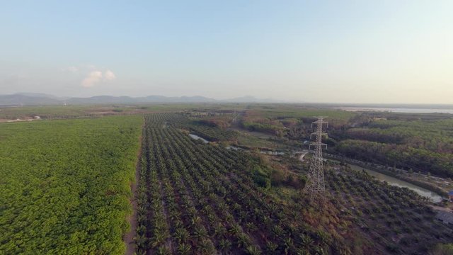 Aerial: Dolly in flight towards a steel overhead power line tower transmitting electrical energy over a long distance in rural landscape.