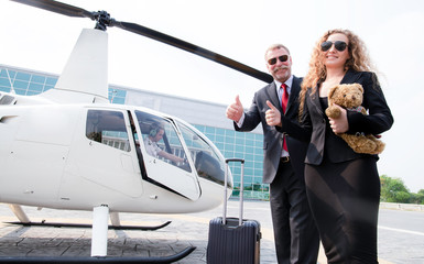 Family next time for us,Happy businessman in dark suit dragging his luggage and businesswomen with teddy bear doll for her child in helicopter platform for going to home,vacation time in holiday.