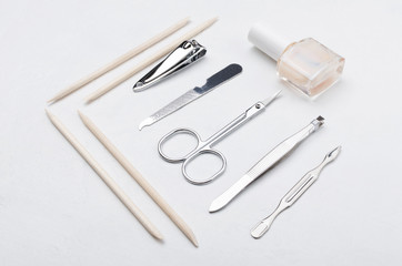 Orangewood sticks, nail polish, scissors, nail clipper, file on the white surface