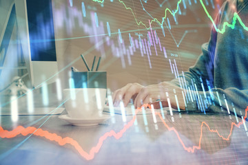 Multi exposure of graph with man typing on computer in office on background. Concept of hard work.