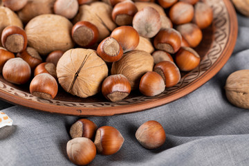 Nuts and walnuts in a pottery bowl on a blue tablecloth