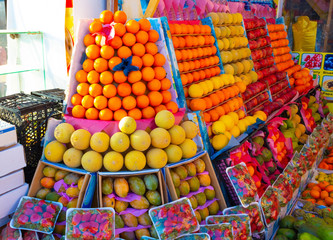 The appetizing showcase of the fruit store with many boxes of mango, oranges, pomegranates, lemons,