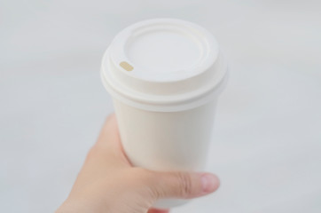 Female hand holding paper coffee cup. Top side view