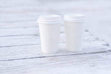 Two paper coffee cups on a wooden table